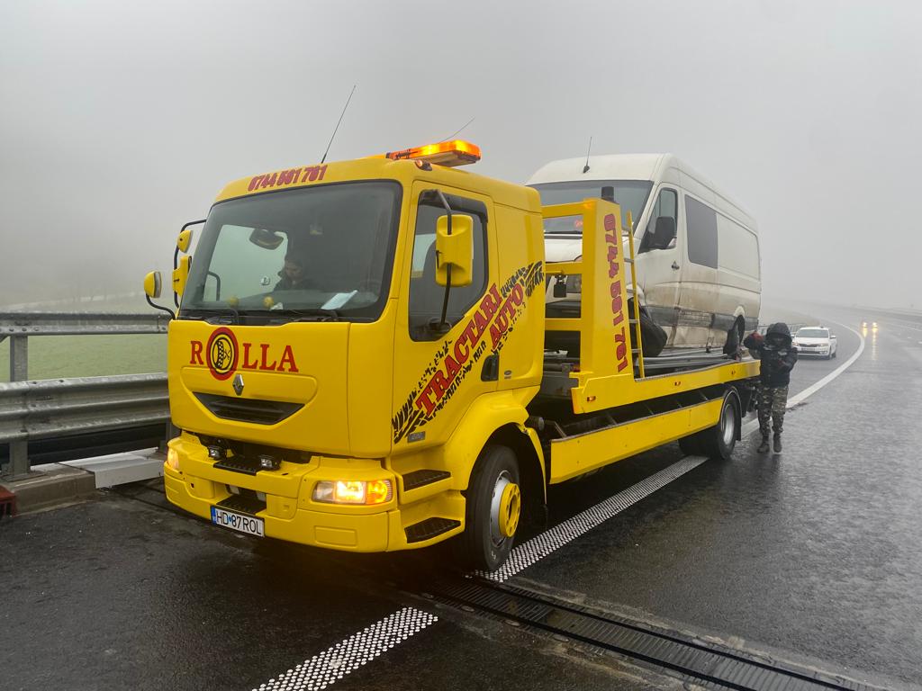 Tractari Alba24 | Transportul unei autoutilitare pe platformă Tractari Alba24 | Platformă galbenă Rolla care transportă o autoutilitară albă pe vreme cu ceață